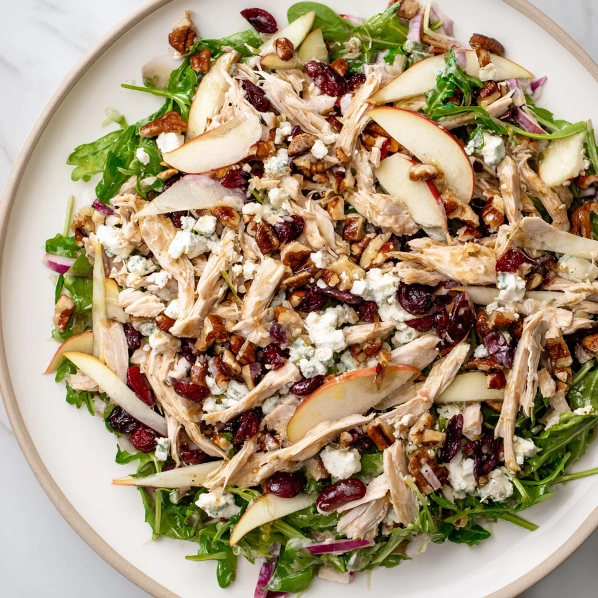 A close-up shot of a colorful Chicken and Apple Winter Salad with pecans and a tangy cider dressing.