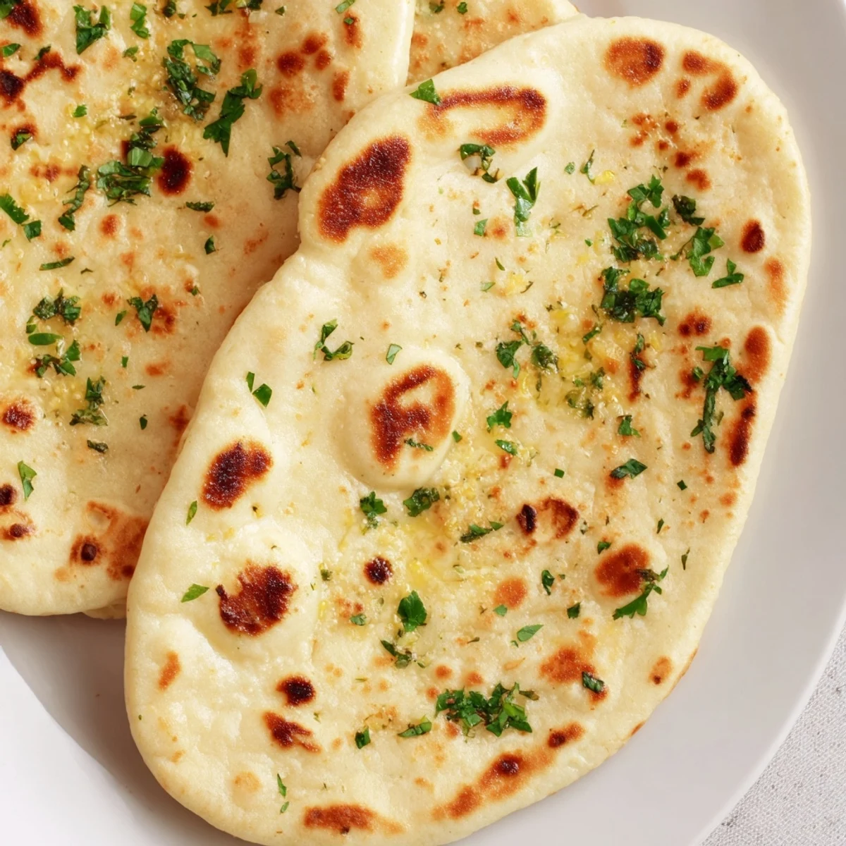 A close-up of freshly cooked homemade garlic naan, steaming hot and ready to be served alongside curry.