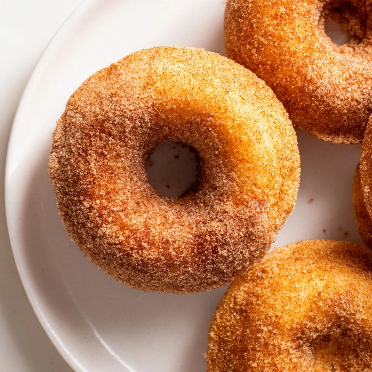 Warm, golden Cinnamon-Sugar Baked Donuts, fresh from the oven, glistening with sweet cinnamon coating.