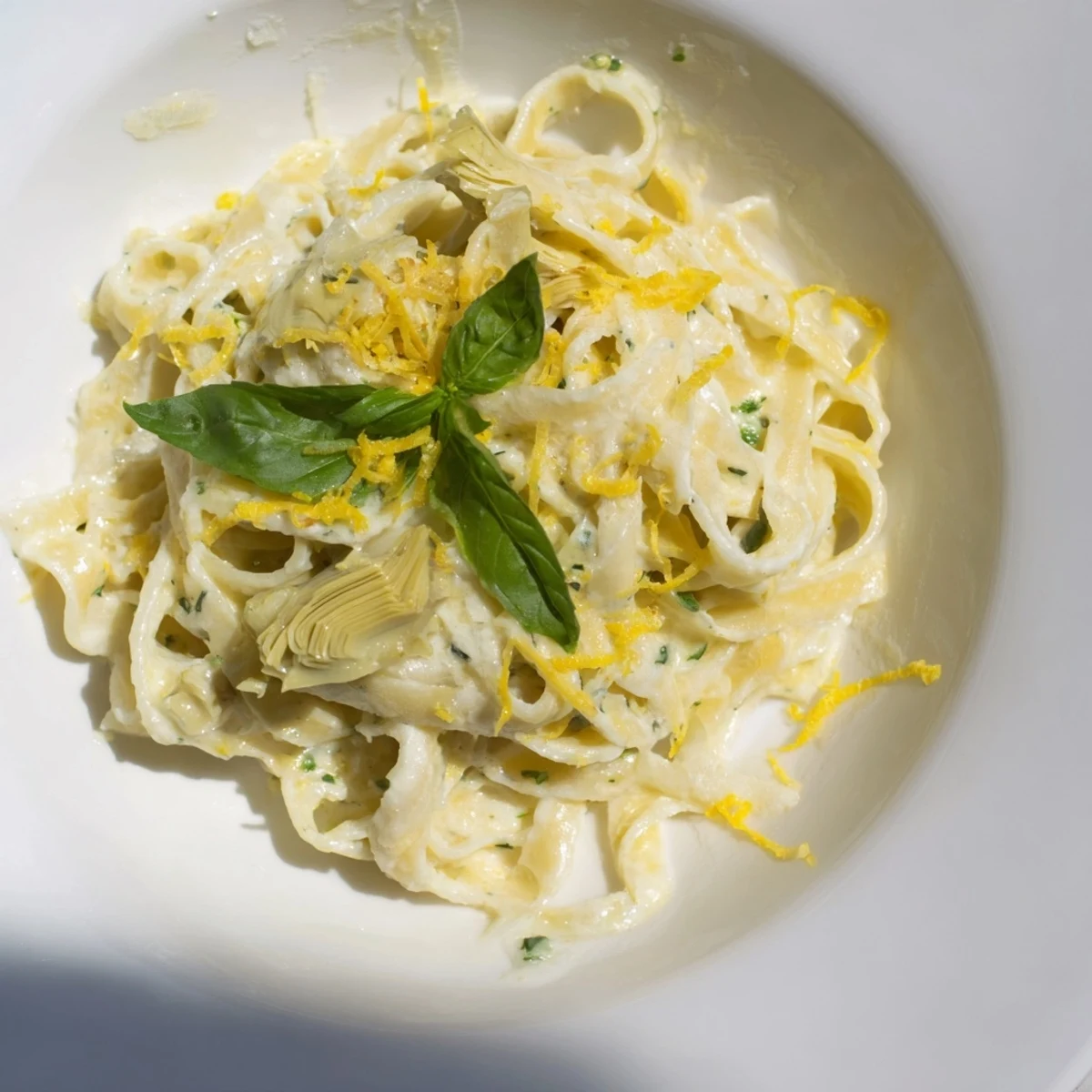 A flavorful bowl of Creamy Lemon Artichoke Pasta, served hot with a sprinkle of Parmesan cheese.