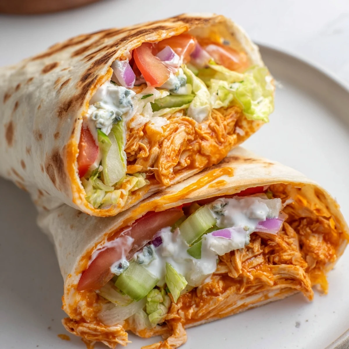 Golden-brown folded buffalo chicken wrap, showing off layers of cheese and crisp lettuce visible.