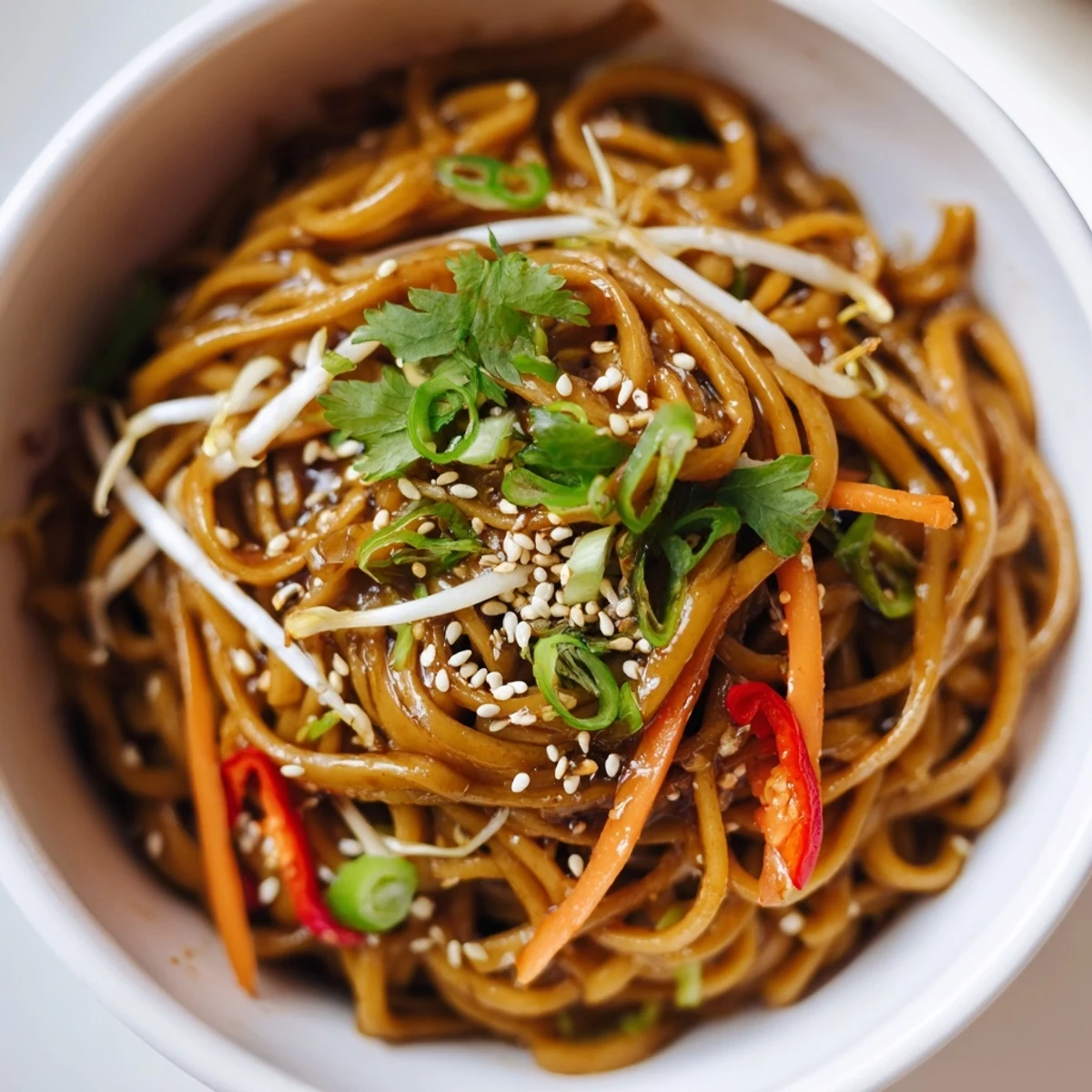 Freshly prepared Asian Garlic Noodle Bowl topped with bean sprouts, sliced red chili, and toasted sesame seeds for a vibrant finish.