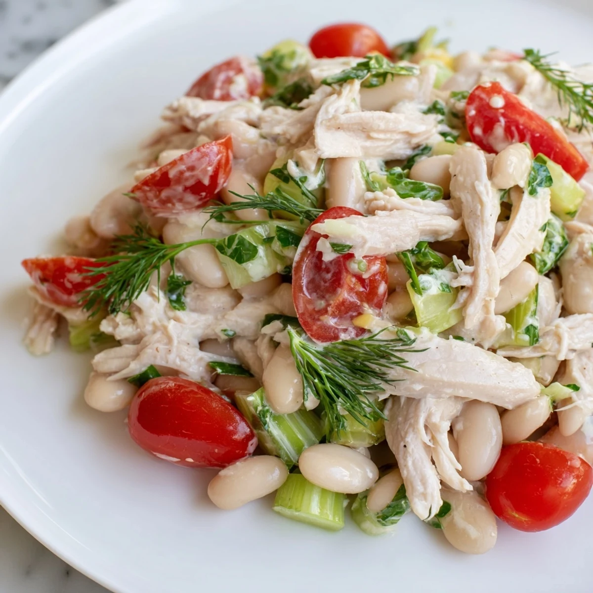 A protein-packed Lemony White Bean Chicken Salad served chilled on a plate, garnished with parsley and lemon zest for a refreshing lunch.  
