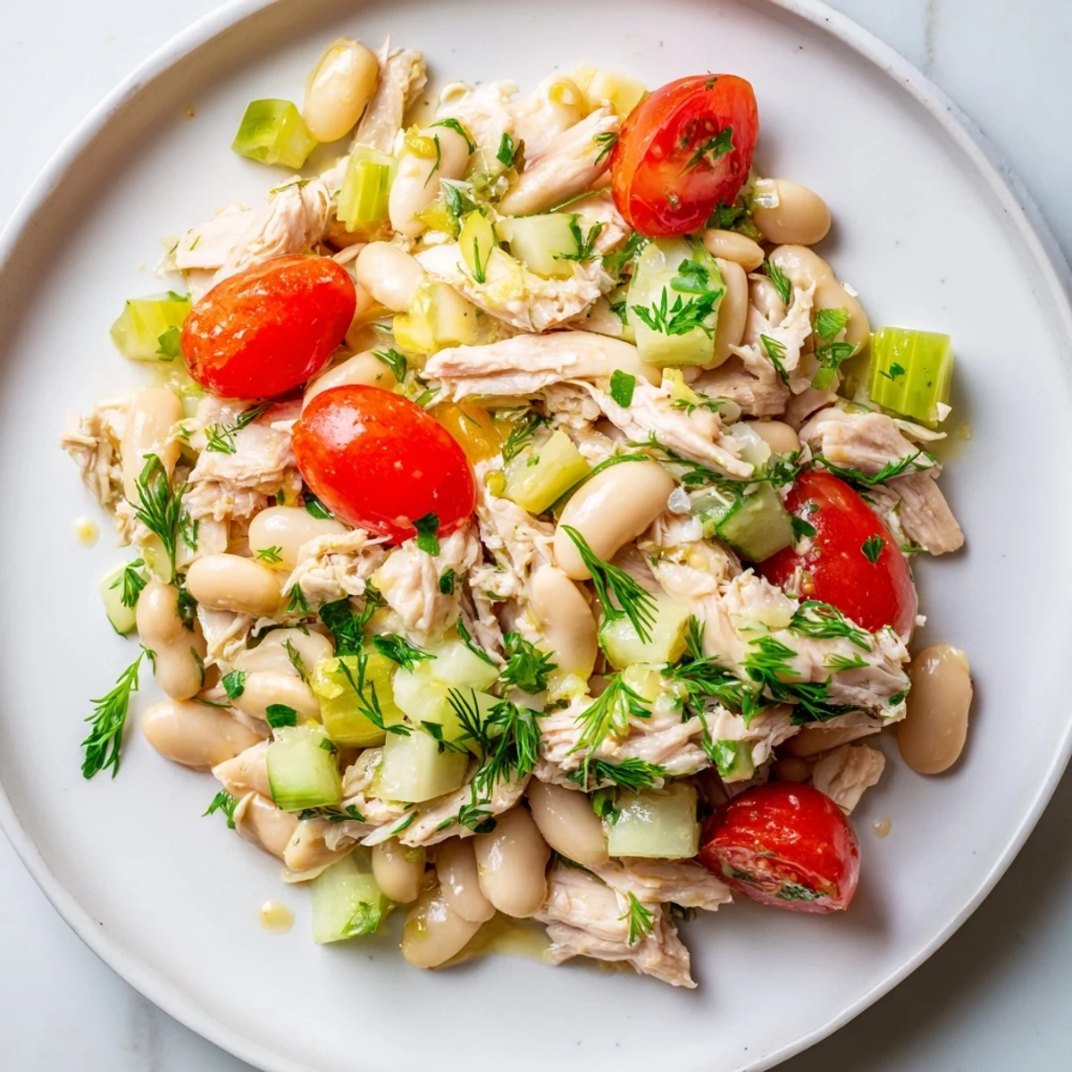 Vibrant bowl of Lemony White Bean Chicken Salad with cherry tomatoes and dill, perfect for a light, gluten-free summer main dish.