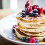 Fluffy ricotta pancakes, light and airy, adorned with fresh berries and a dusting of powdered sugar.