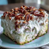 A slice of Butter Pecan Tres Leches Cake reveals fluffy whipped cream, a drizzle of caramel, and crunchy pecans.