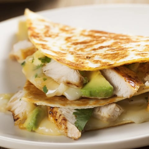 A golden-brown Chicken Avocado Quesadilla is cut into wedges, revealing a filling of grilled chicken, creamy avocado mash, and melted cheese.