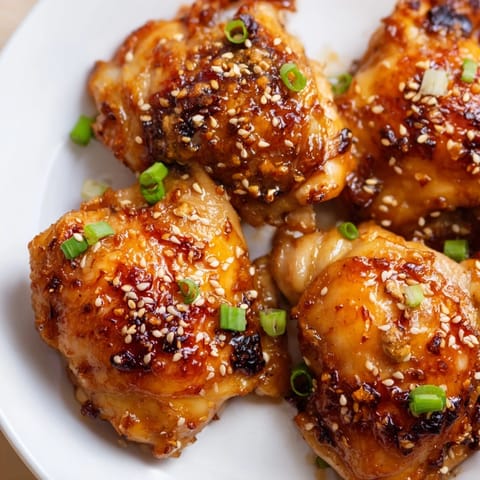 Sizzling golden chicken thighs coated in a sweet and savory honey garlic glaze, ready to serve over steamed rice and vegetables.  