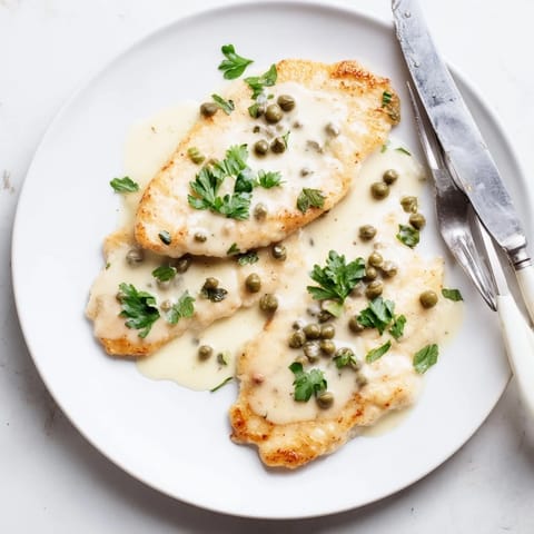 Tender Chicken Piccata with bright lemon and parsley garnish on a white plate.