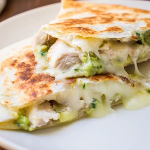 This close-up shot showcases the crispy tortilla texture and gooey interior of a homemade Chicken Avocado Quesadilla.