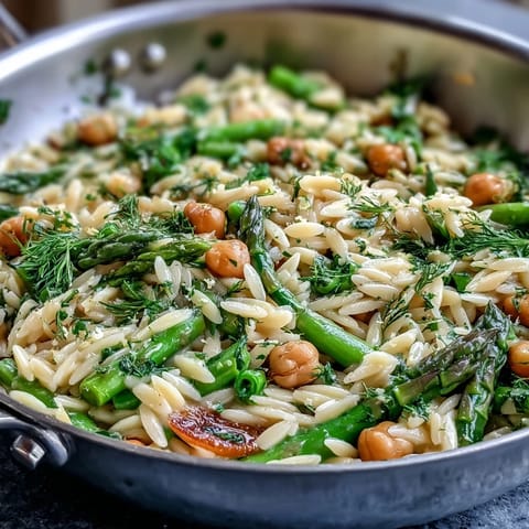 Creamy Mediterranean-inspired orzo pasta dish with asparagus, zucchini, and sugar snap peas in a zesty lemon broth.  