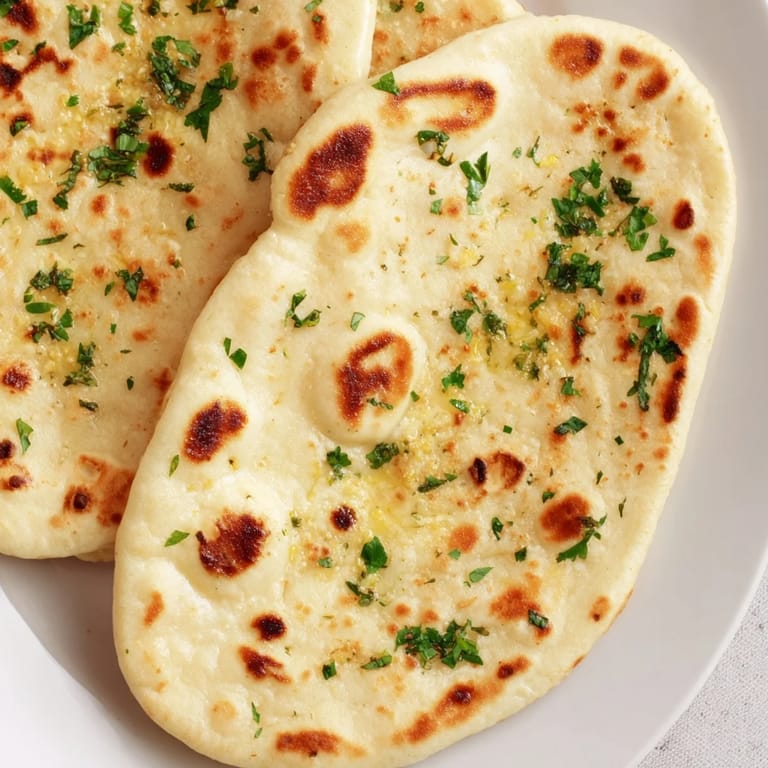 A close-up of freshly cooked homemade garlic naan, steaming hot and ready to be served alongside curry.