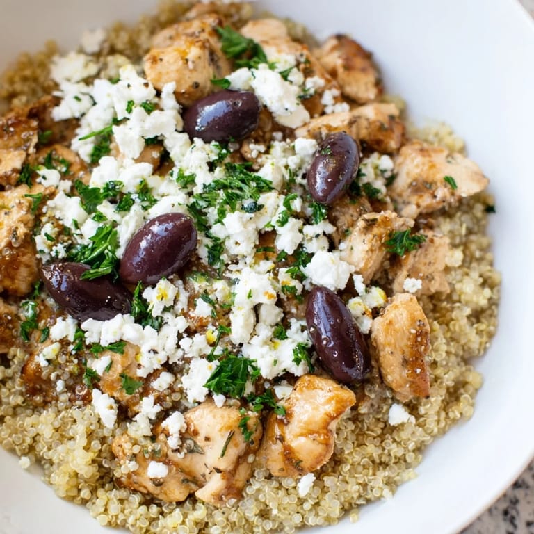 Healthy Mediterranean Chicken Bowl topped with crumbled feta, Kalamata olives, red onion, and fresh parsley, drizzled with a zesty lemon dressing.
