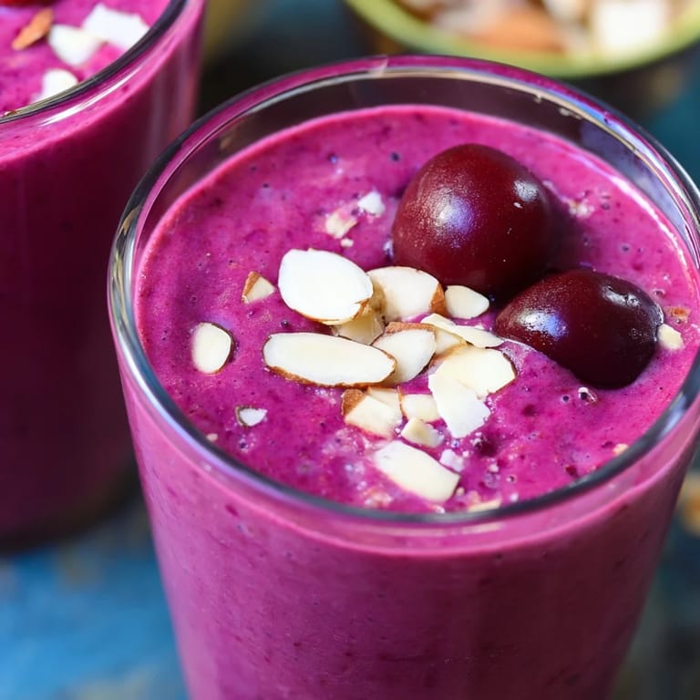Close-up of a creamy Cherry Almond Smoothie topped with a swirl and a sprinkle of chopped almonds.