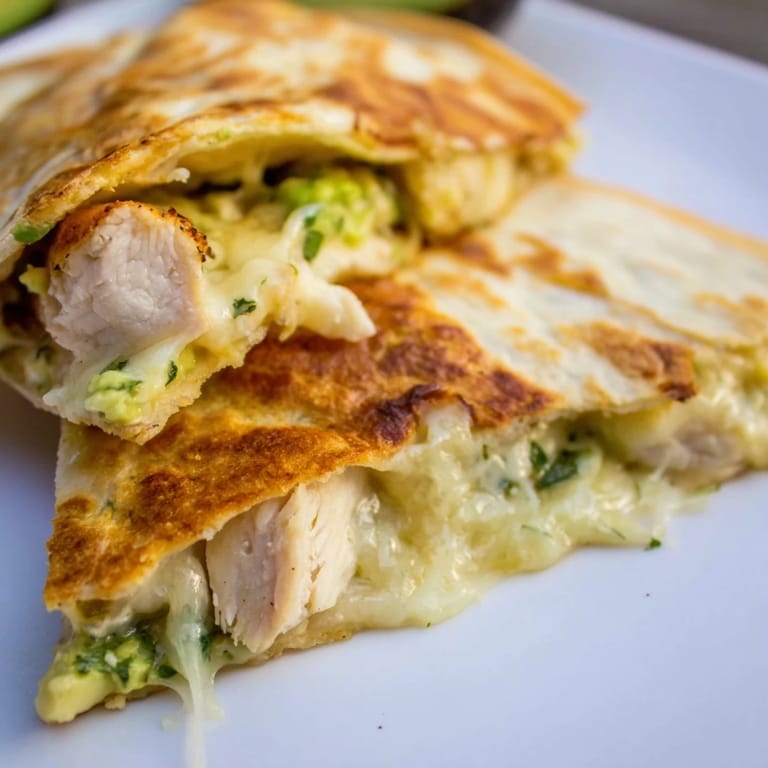 A vibrant serving of Chicken Avocado Quesadilla sits on a plate, garnished with fresh cilantro and a side of salsa.