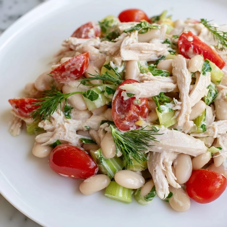 A protein-packed Lemony White Bean Chicken Salad served chilled on a plate, garnished with parsley and lemon zest for a refreshing lunch.  