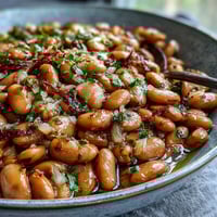 Slow-simmered pinto beans with garlic and onions in a rustic pot, ready to serve as a hearty side dish or taco filling.