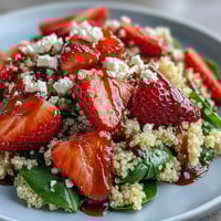 A colorful spring salad with ripe strawberries, crumbled feta, and fluffy quinoa, tossed in a tangy balsamic dressing.