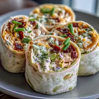 Creamy Buffalo chicken and cheese filling wrapped in soft tortillas, sliced into colorful pinwheels for a zesty appetizer.  