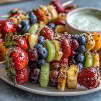 Rainbow Fruit Skewers with Honey Dip: Colorful fruit skewers arranged in rainbow order, served with a creamy honey-yogurt dip for a refreshing summer snack.