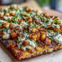 Charred corn sits atop a flatbread, drizzled with jalapeño crema.